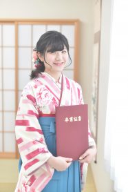クリーム地にピンクのストライプ柄の着物×水色の袴を着て卒業証書を持った女の子