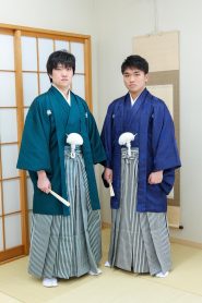 成人式の紋付き袴で人気の高い深緑色と紺色の羽織着物におそろいの縞の袴を着付けた男子のツーショット