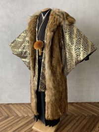 毛皮っぽい濃いベージュに黒毛の混じるタイプの成人式用ファーコート。紋付袴によくマッチしている