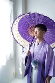 藤色から紫のグラデーション着物にシルバーの袴を着て、紫の番傘を持った成人式の男子