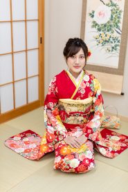 明るい赤地に桜の描かれたかわいい振袖姿の女性