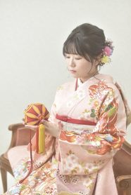 淡いピンクの古典柄振袖を着て毬を持つ女性
