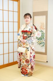 薄ベージュのくすみカラー振袖。柄はオレンジ臙脂のレトロモダンな雰囲気